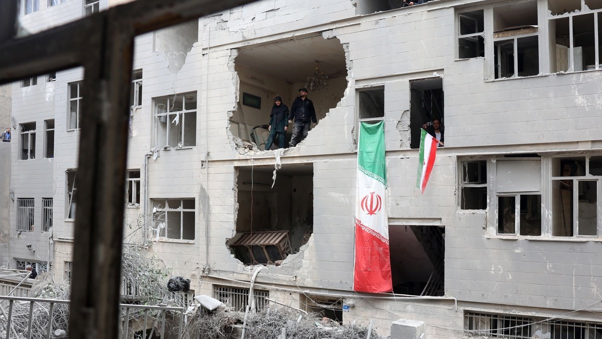 Ciudadanos iraníes se encuentran dentro de su edificio residencial dañado en el sur de Teherán, el 15 de marzo de 2026.