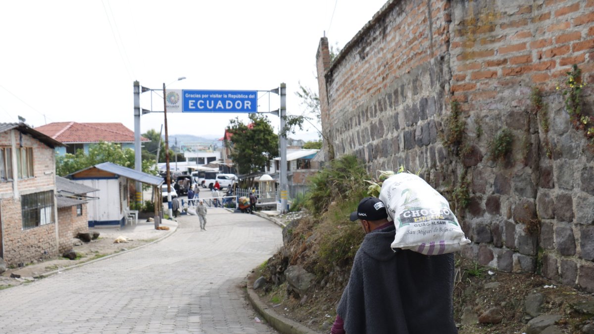 Un hombre carga un costal con productos agrícolas y lo atraviesa hasta cruzar el paso fronterizo.