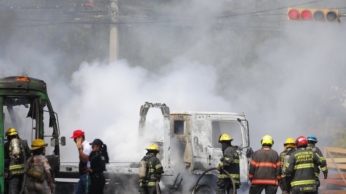 Integrantes del Cuerpo de Bomberos de Guadalajara intentan apagar un vehículo incendiado este domingo 22 de febrero, tras el accionar de grupos narcodelictivos.