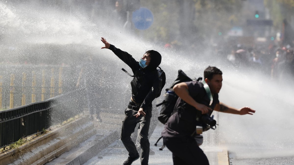 Manifestantes e integrantes de la Policía de antidisturbios de Carabineros de Chile se enfrentan durante una manifestación el 26 de marzo de 2026, en Santiago (Chile).