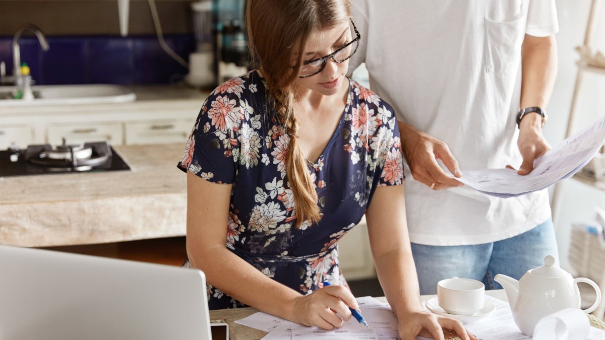 Una persona pone por escrito sus ingresos y apunta todo lo que tiene que pagar.