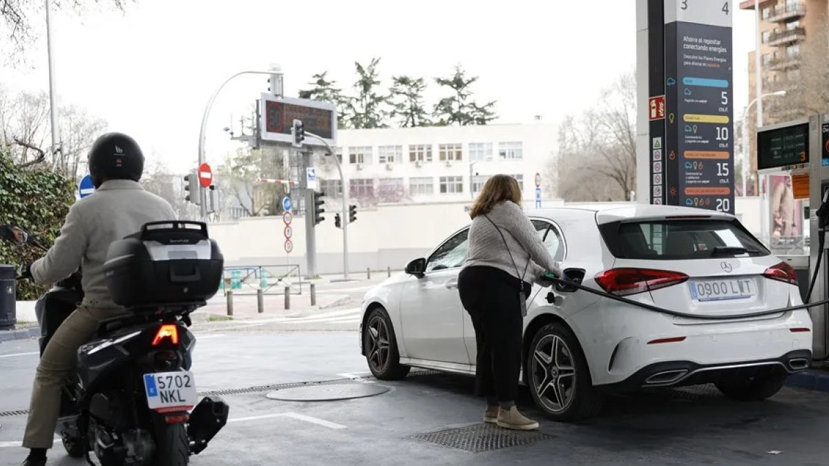 Una mujer llena de combustible su carro.