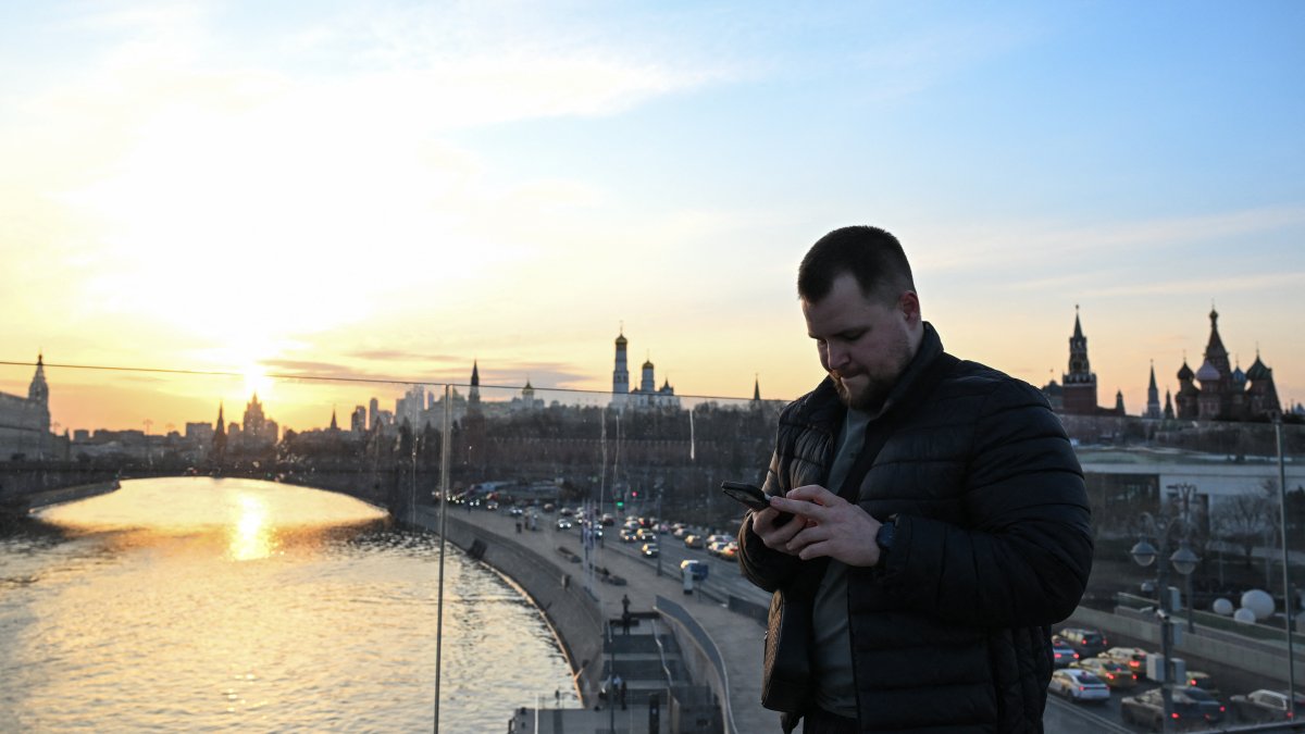 Moscú. Un hombre usa su teléfono inteligente en el puente flotante (Puente Paryashiy) en el parque Zaryadye, en el centro de Moscú.