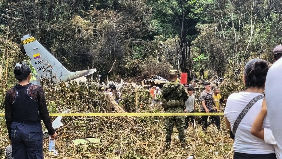 Varias personas y soldados se encuentran junto a los restos de un avión Hércules de la Fuerza Aérea que se estrelló durante el despegue, en Puerto Leguizamo (Colombia), el 23 de marzo de 2026.