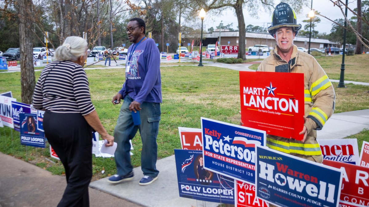 Personas caminan junto a anuncios de candidatos durante la jornada electoral en la entrada del Centro Comunitario este martes, en Houston (Estados Unidos).