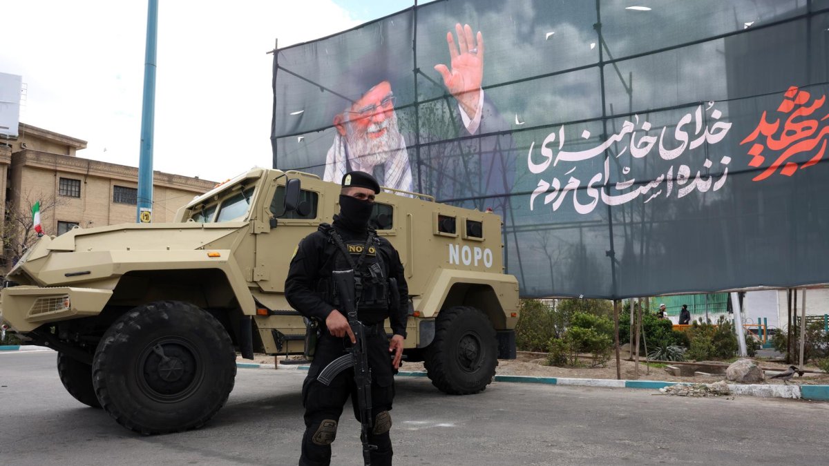 Un miembro de las fuerzas de seguridad iraníes monta guardia junto a una pancarta en honor al exlíder supremo iraní Ali Khamenei, en Teherán, Irán, el 30 de marzo de 2026.