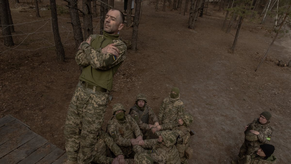 Entrenamiento. Un recluta ucraniano cae al suelo mientras sus compañeros se preparan para atraparlo durante un entrenamiento militar básico.