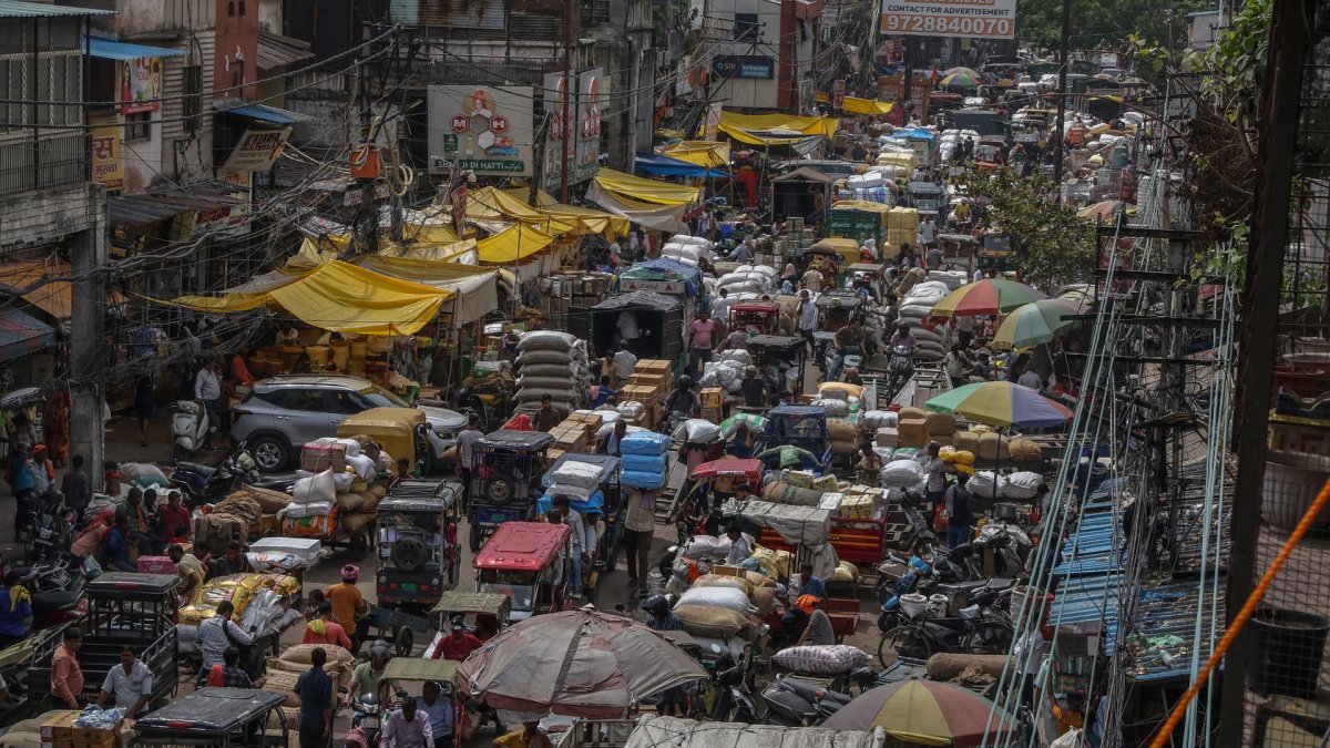 Personas y vehículos transitan por una calle congestionada en un mercado mayorista del casco antiguo de Nueva Delhi.