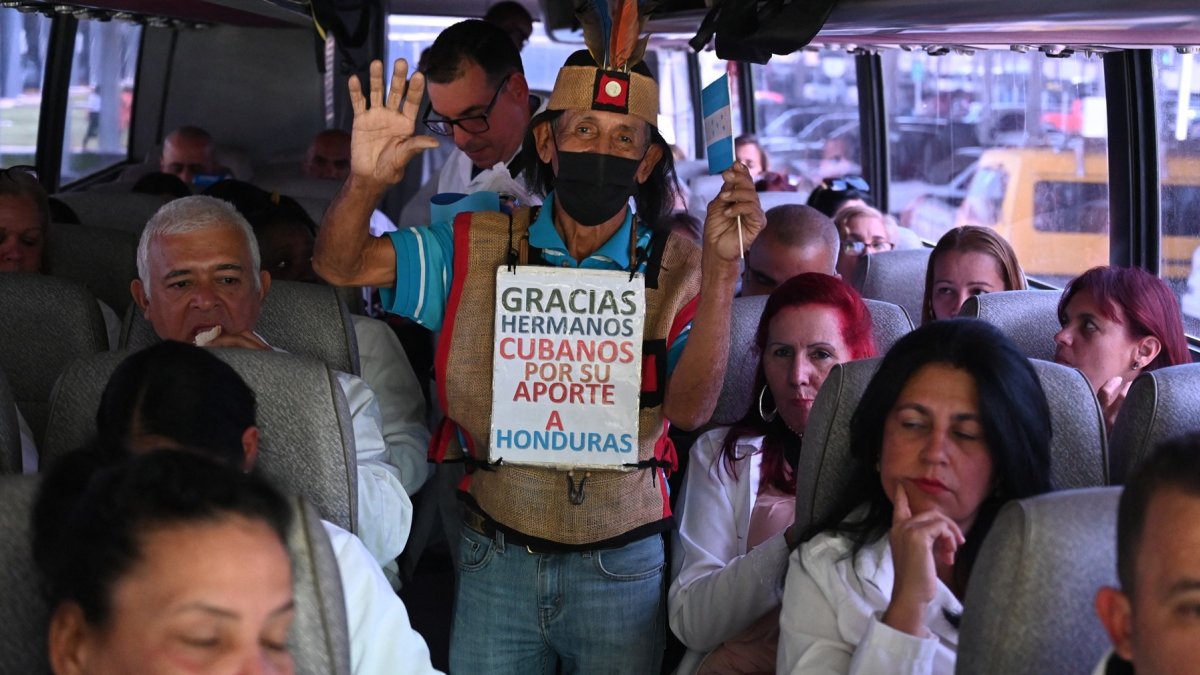 Un hombre saluda a médicos cubanos en un autobús tras su llegada al Aeropuerto Internacional de Palmerola, a 50 km al norte de Tegucigalpa, el 27 de febrero de 2024.