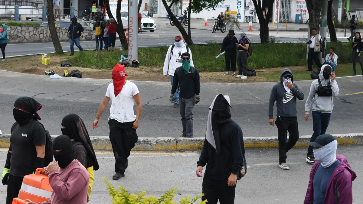 Encapuchados caminan durante una manifestación el 7 de abril de 2026, afuera de la Universidad de San Carlos de Guatemala (Guatemala).