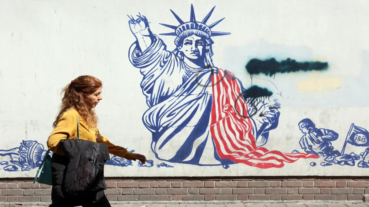 Una mujer camina junto a un mural antiestadounidense cerca de la antigua Embajada de EE. UU. en Teherán.