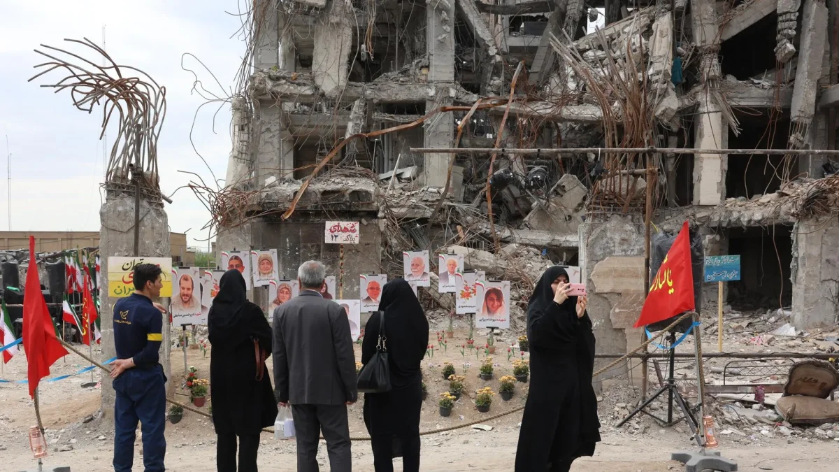 Varias personas observan fotos de fallecidos en ataque aéreo estadounidense-israelí contra edificio residencial, expuestas frente al mismo edificio en Teherán, el 13 de abril de 2026.