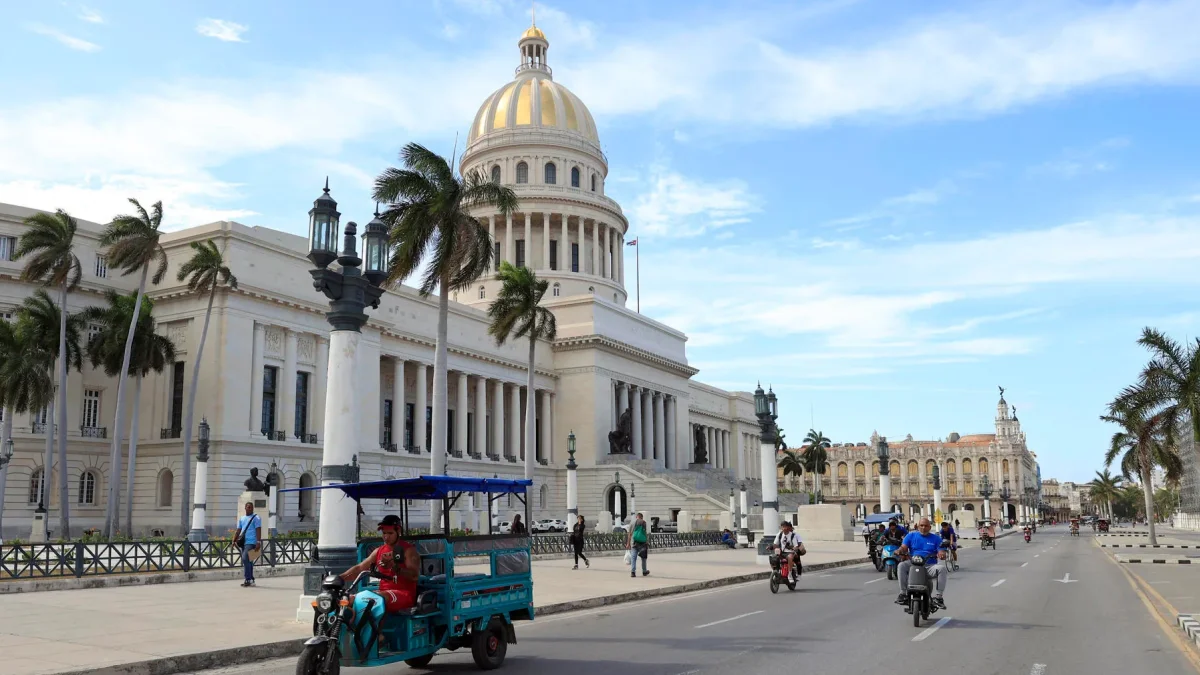 Un triciclo y varias motocicletas eléctricas circulan frente al Capitolio este martes 14 de abril de 2026,en La Habana (Cuba).