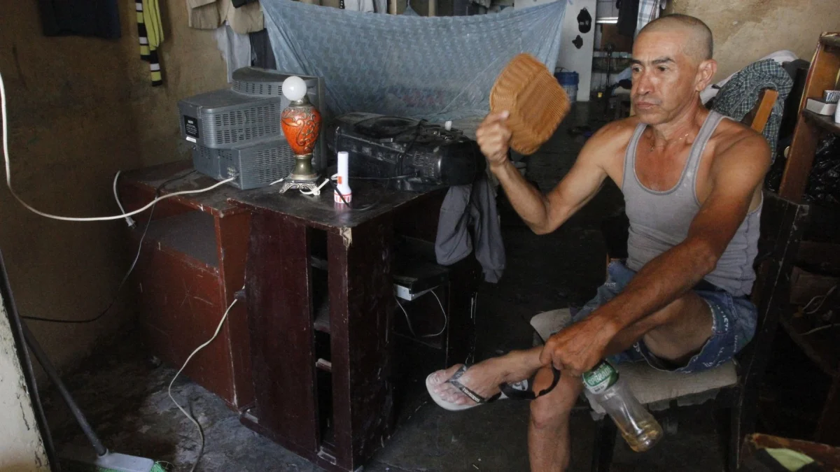 En el sur de Guayaquil, moradores del suburbio intentaron aliviar el calor con cualquier objeto ante la falta de energía eléctrica, que les impedía encender ventiladores.