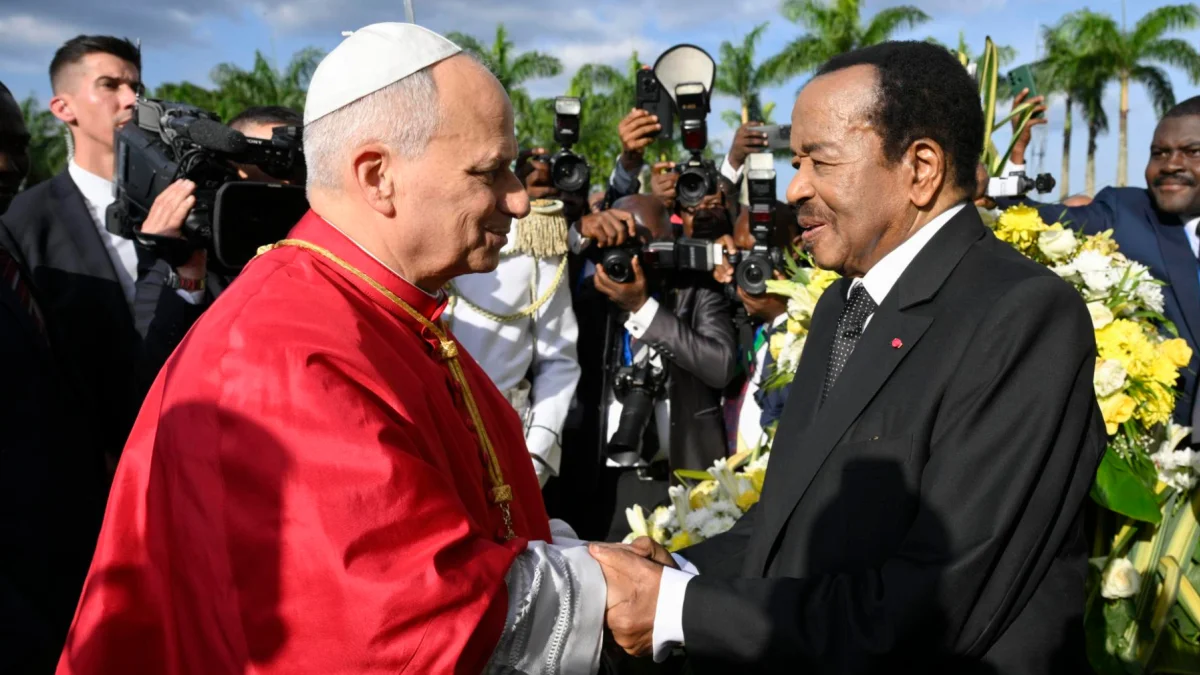 El papa León XIV estrecha la mano de un líder político en Camerún, durante su mensaje contra el uso de la fe con fines bélicos.
