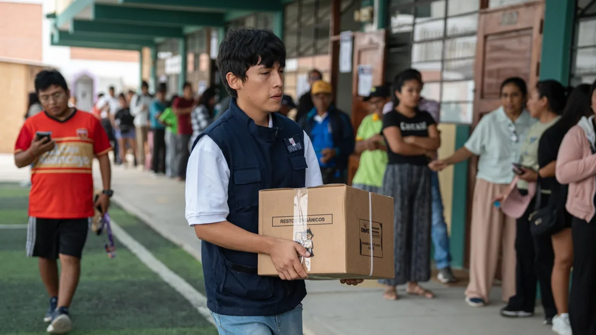 Integrante de la Oficina Nacional de Procesos Electorales (ONPE) carga una caja para empezar la instalación de una de las mesas de votación en un colegio de Lima.