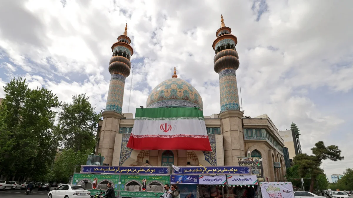Varios automovilistas pasaron junto a la mezquita del Imam Sadiq (AS), cuya fachada lucía una enorme bandera iraní, en la plaza Palestina de Teherán.