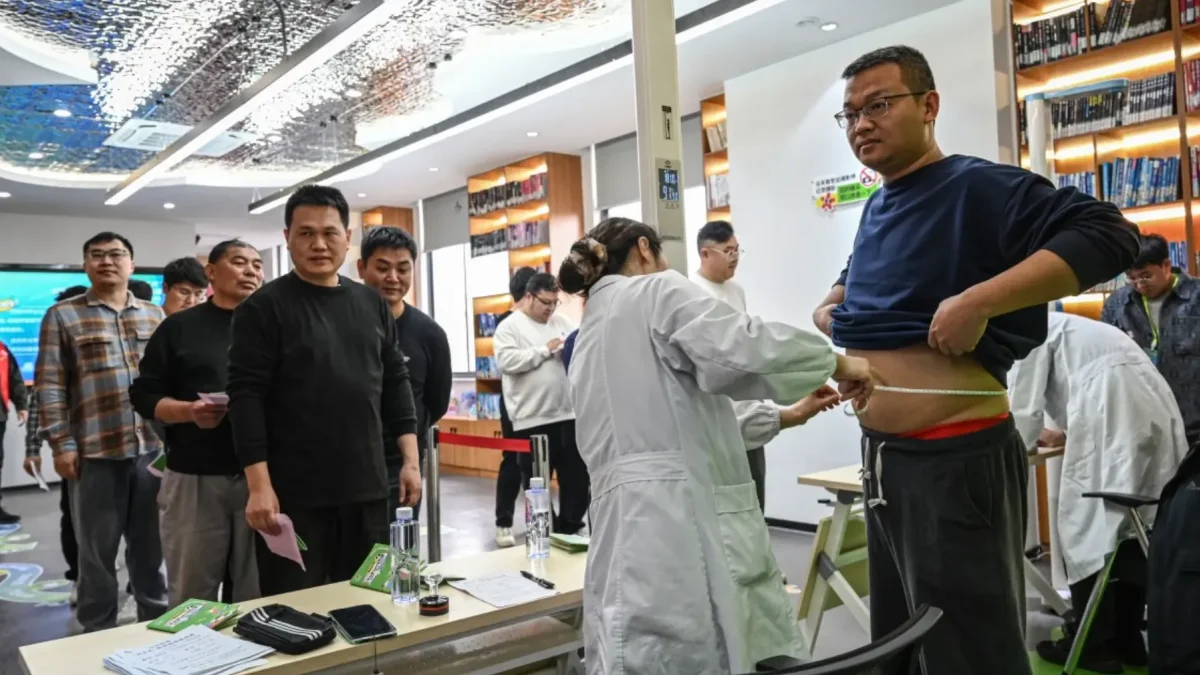 Participantes masculinos haciendo fila para pesarse y medirse la cintura en un centro comunitario local en Wuxi, en la provincia de Jiangsu, al este de China.