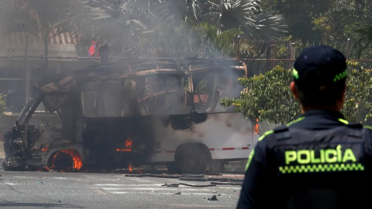 Un integrante de la Policía de Colombia observa un vehículo afectado por una explosión este 24 de abril de 2026, en Cali (Colombia).