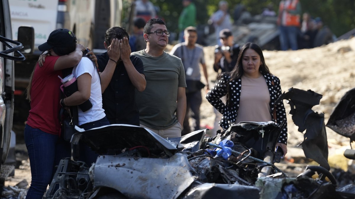 Familiares de las víctimas del atentado ocurrido en la Vía Panamericana lloran este domingo frente a los escombros de los vehículos destruidos en Cajibío (Colombia).