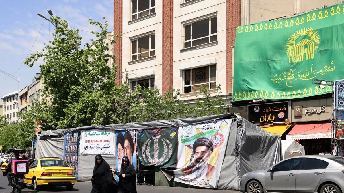 Mujeres caminan junto a pancartas instaladas en Teherán con imágenes del asesinado líder supremo de Irán, el ayatolá Ali Khamenei (izquierda), y del líder supremo, el ayatolá Mojtaba Khamenei.