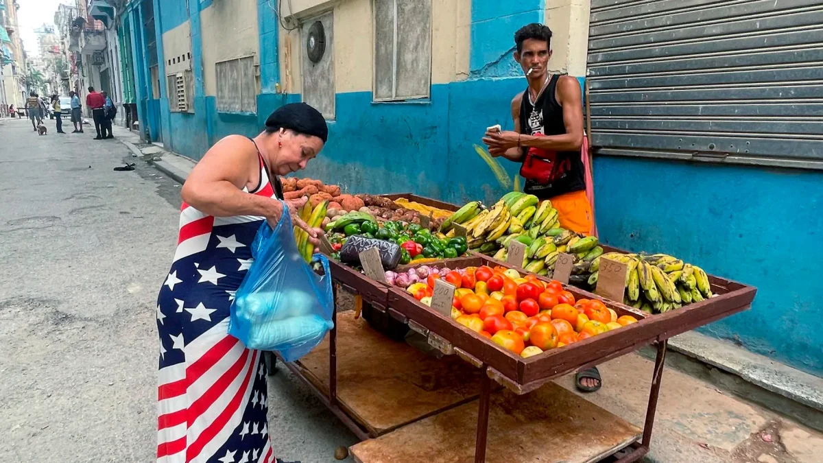 Una mujer vestida con los colores de la bandera de Estados Unidos compra frutas a un vendedor ambulante este viernes, en una calle de La Habana (Cuba).