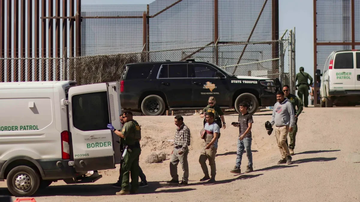 Migrantes detenidos son llevados por miembros de la Patrulla Fronteriza estadounidense a un vehículo, junto al muro fronterizo en El Paso, Texas (EE.UU).