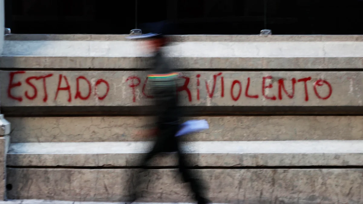 Un policía camina frente a un grafiti en La Paz, en medio de las protestas que marcan la primera crisis política del Gobierno de Rodrigo Paz.