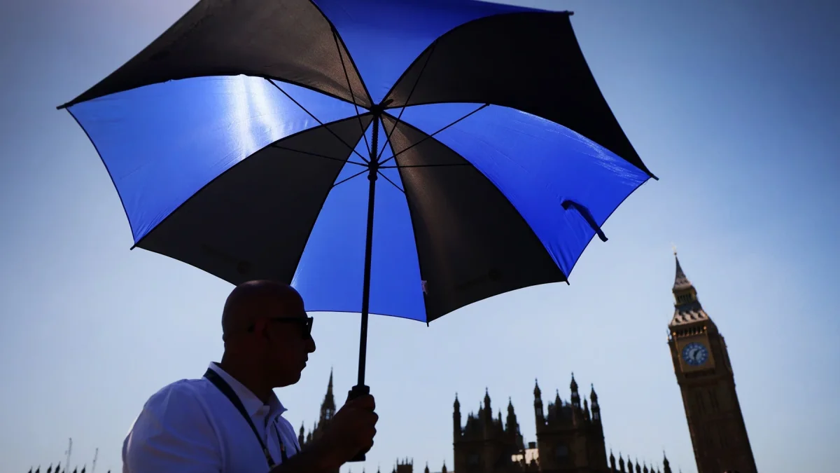 Un hombre se protege del sol con un paraguas en Londres.