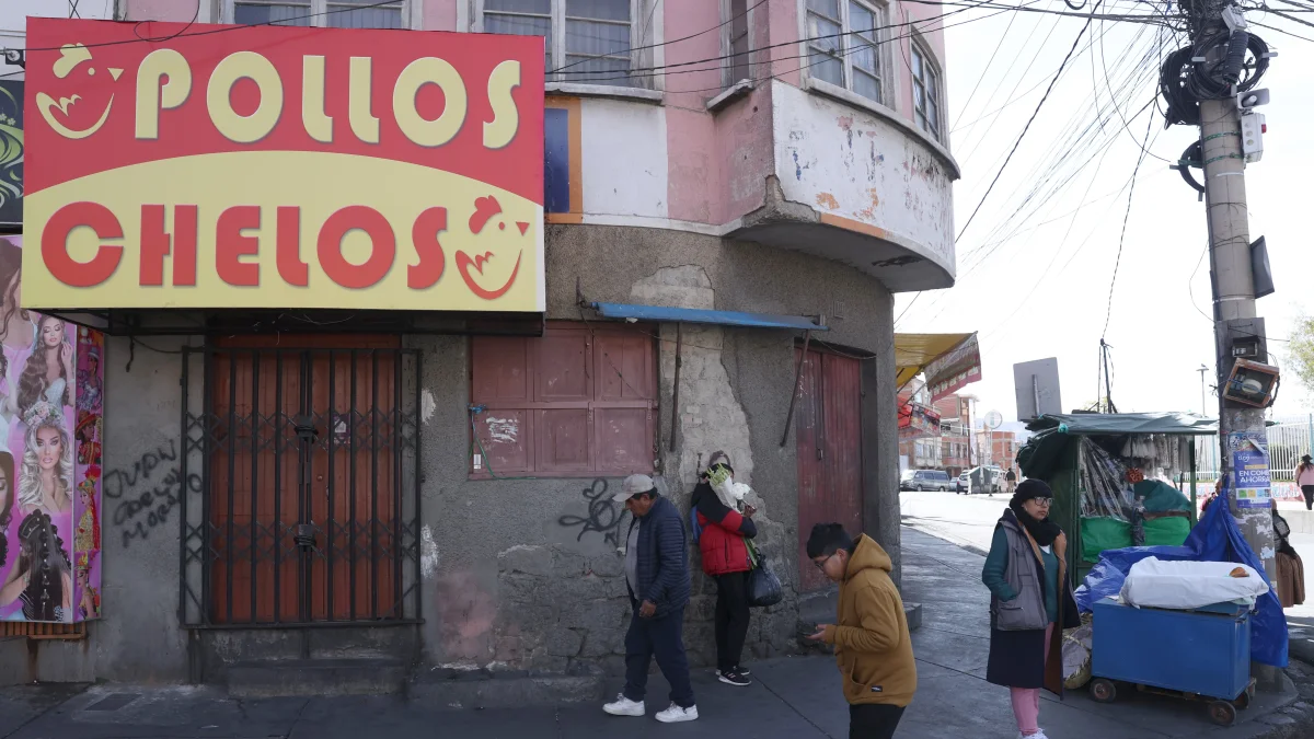 Unas personas pasan al pie de un negocio cerrado por el paro que hay en Bolivia.
