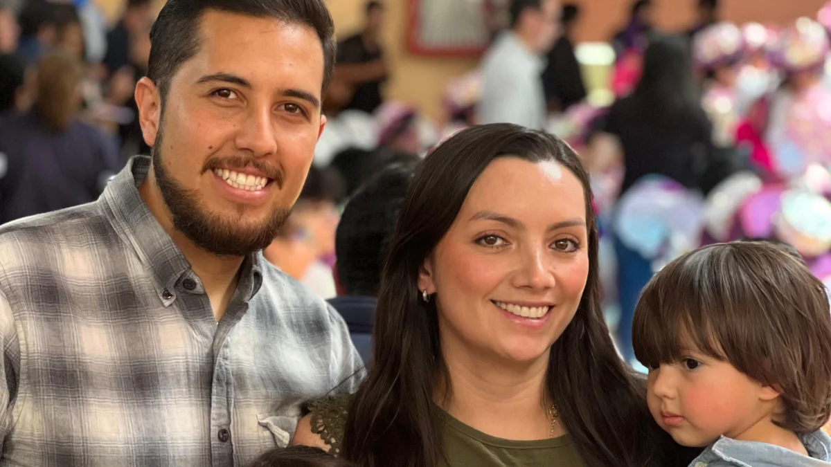 Mathias, de 3 años, junto a sus padres en una reunión con ambiente festivo.