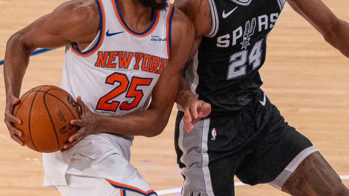 El dorsal '25' de los Knicks bajo la presión defensiva del '24' de los Spurs en plena acción.