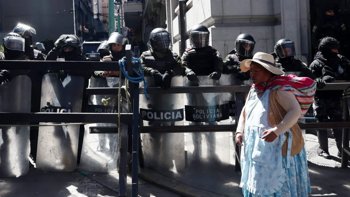 Una mujer aimara camina frente a un grupo de policías durante una protesta por quinta semana consecutiva este 1 de junio de 2026, en La Paz (Bolivia).