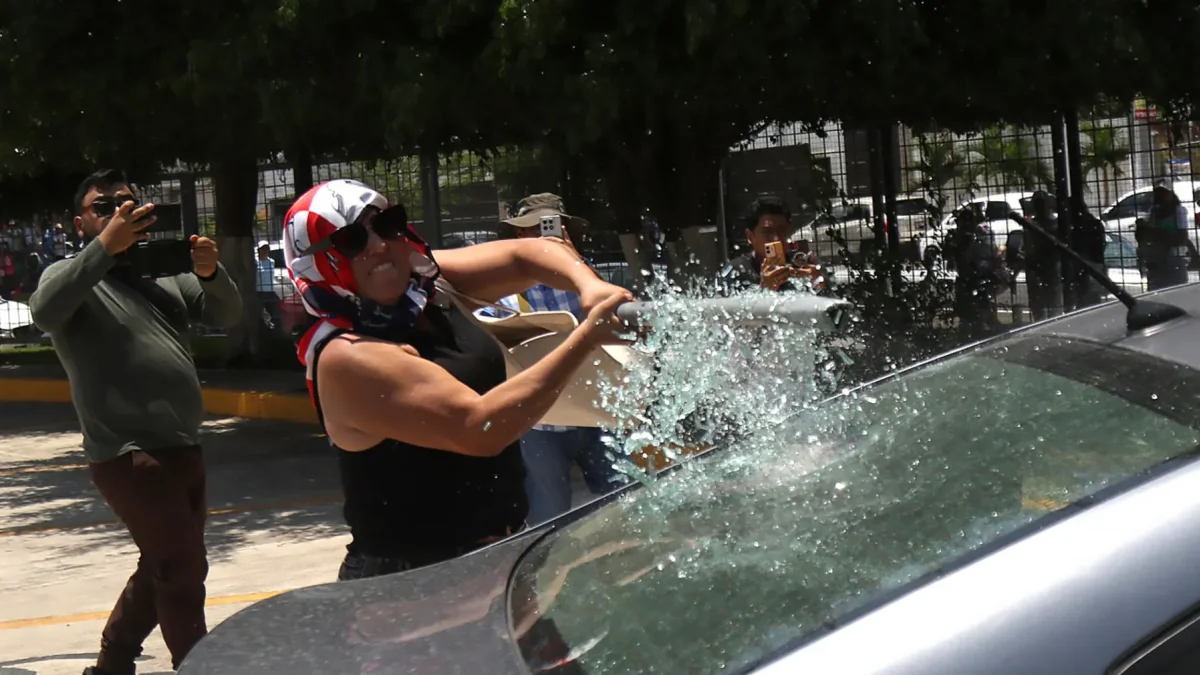 Una persona vandaliza un vehículo este martes, durante una protesta de integrantes de la Coordinadora Nacional de Trabajadores de la Educación (CNTE), en Chilpancingo (México).