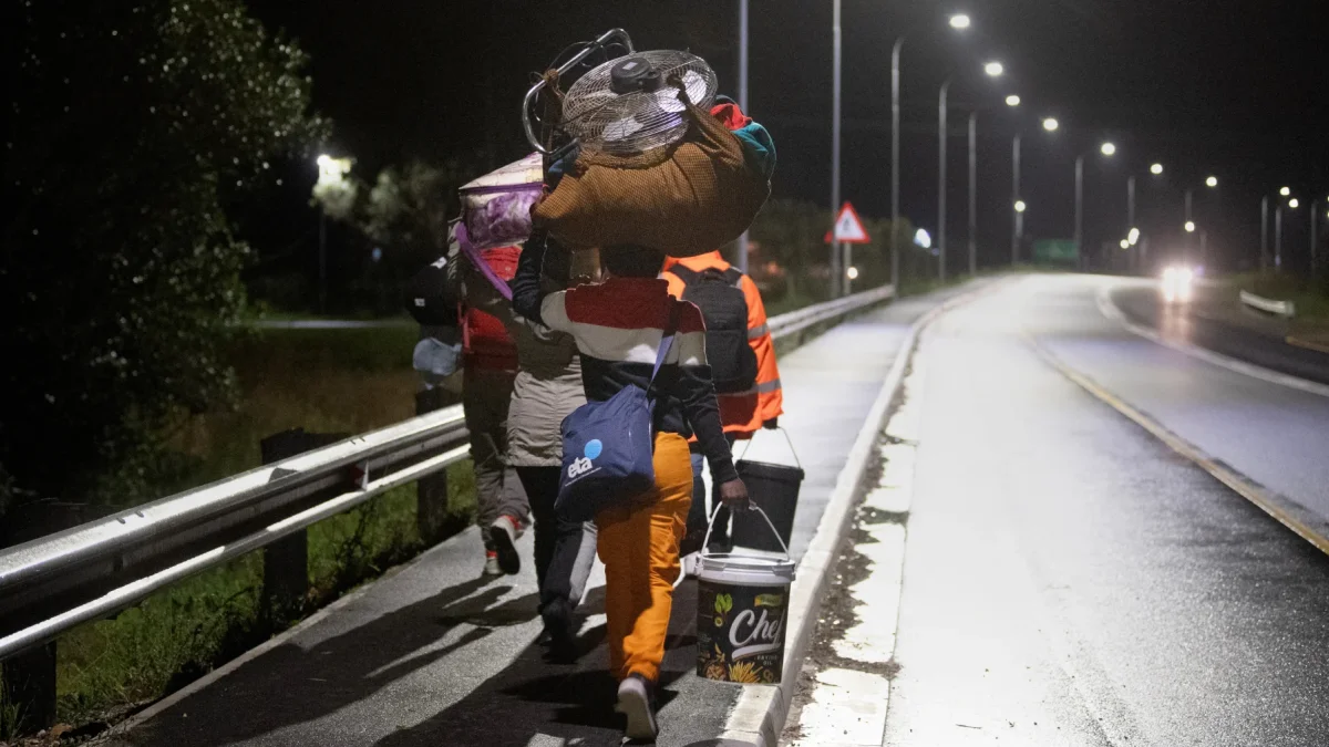 Inmigrantes cargando sus pertenencias caminan por una calle de Stanford, a unos 120 kilómetros de Ciudad del Cabo.