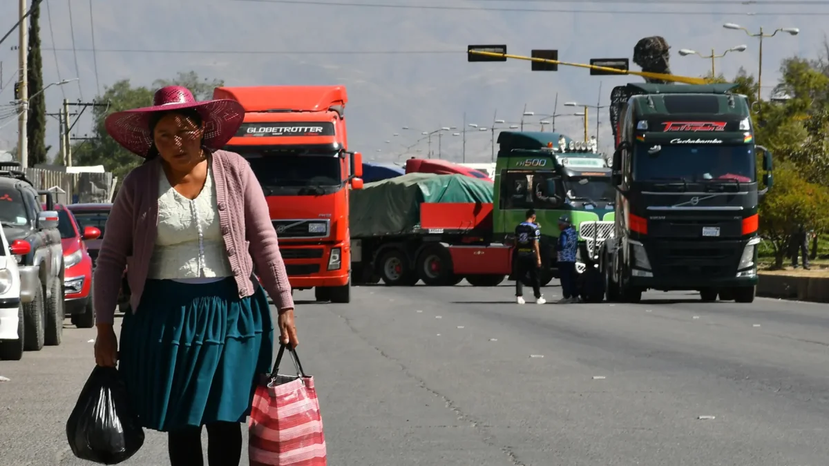 Una mujer quechua camina frente a vehículos de una caravana de transportistas para exigir el levante de los bloqueos de carreteras este lunes, en Cochabamba (Bolivia).