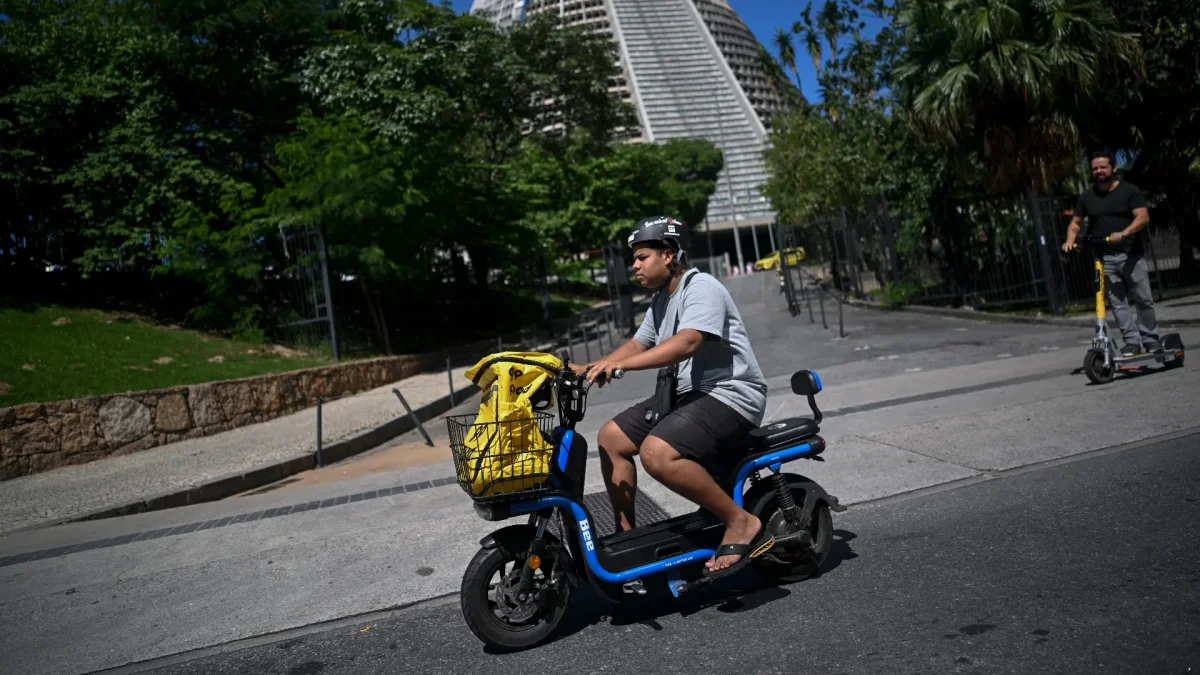 El repartidor de comida a domicilio Joao Paulo Teixeira, de 20 años, entrega un pedido para la aplicación 99Food en su bicicleta eléctrica en el centro de Río de Janeiro