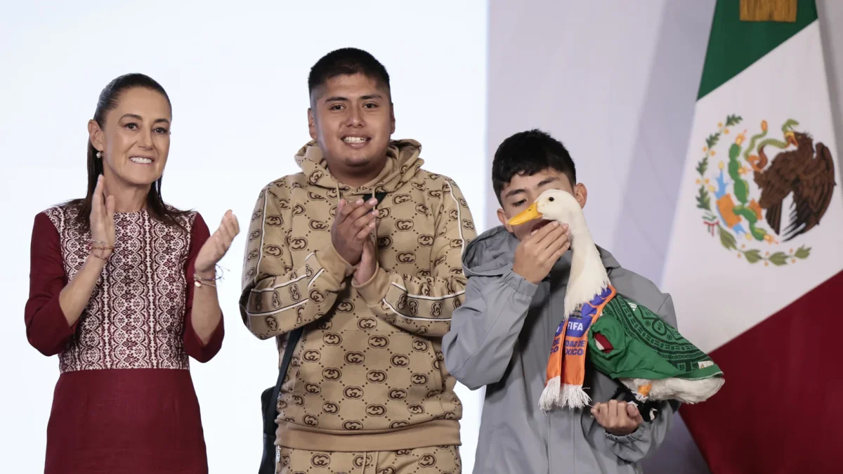 El pato Merlín, vestido con una camiseta de la Selección Mexicana de Fútbol, junto a sus familiares Karla Gómez (i) y Cristian (2-d) durante una visita a la presidenta de México, Claudia Sheinbaum.