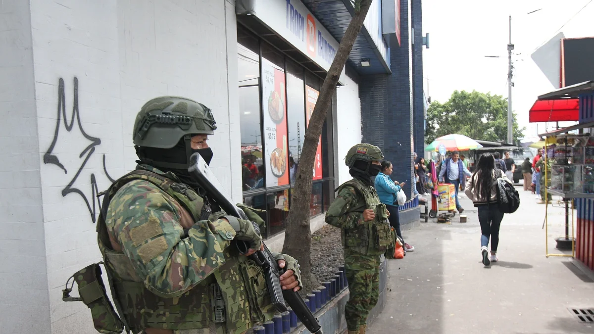 Dos militares resguardan una zona de afluencia de civiles en una ciudad.