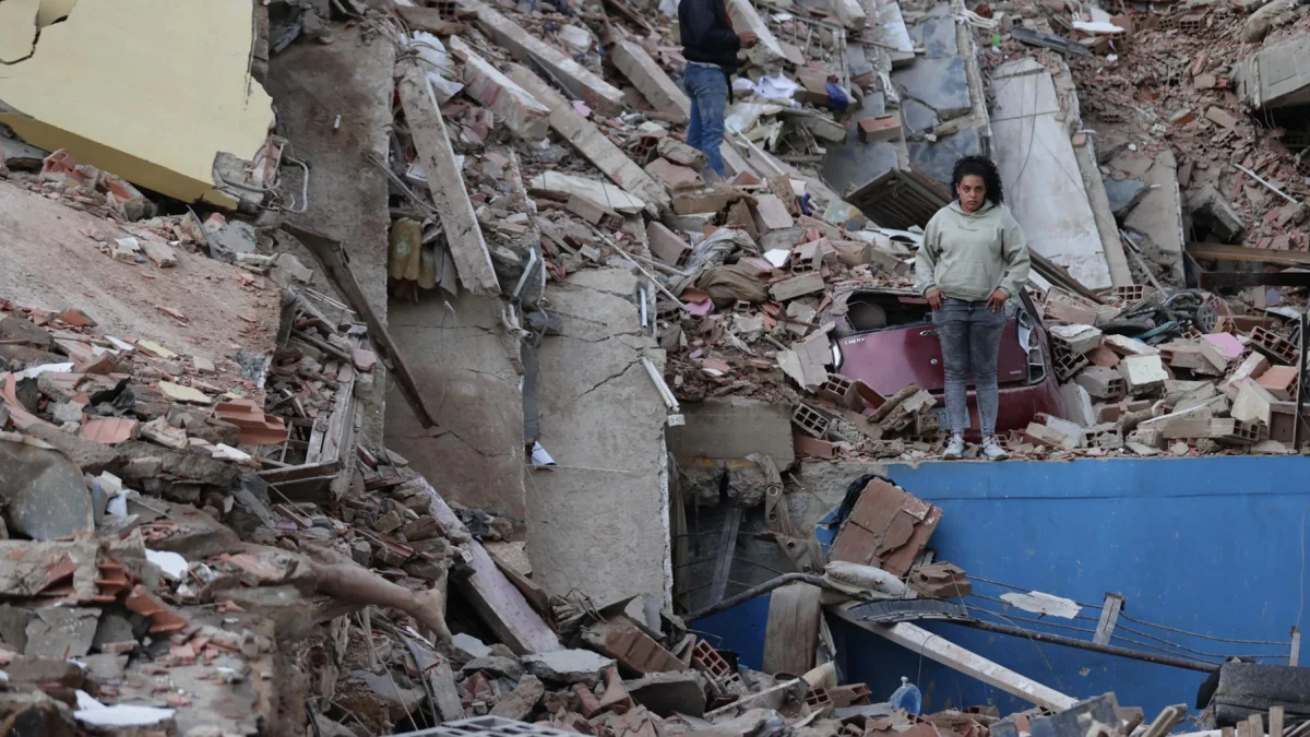 Residentes caminan entre los escombros de edificios derrumbados tras los terremotos en Catia La Mar, estado La Guaira.
