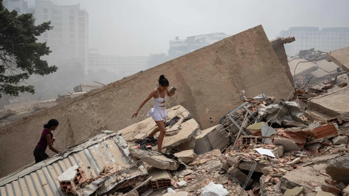 Personas caminan entre los escombros de edificios colapsados tras los terremotos en La Guaira, Venezuela.