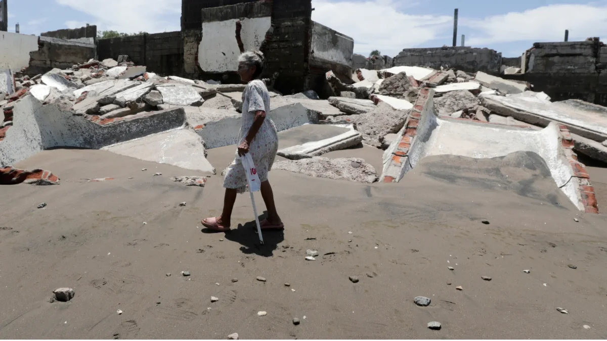 Una habitante de la aldea camina frente a escombros de casas destruidas en Cedeño, al sur de Honduras. El poblado lleva 30 años sufriendo el avance del mar.