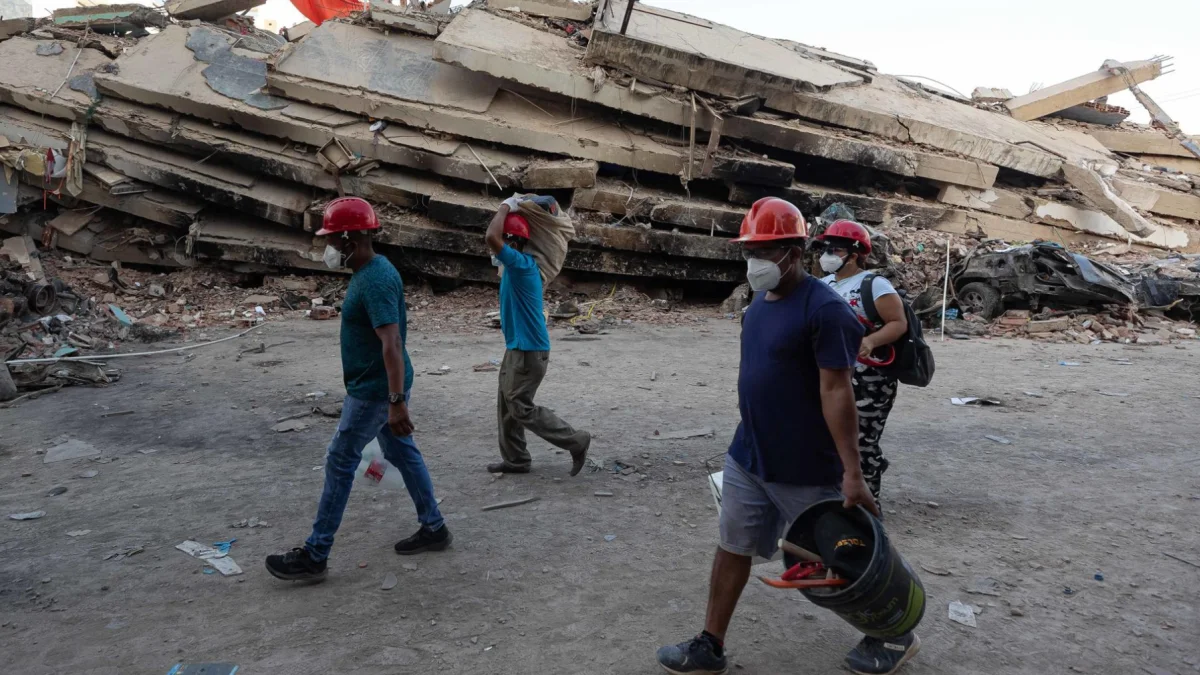 Personas caminan frente a los escombros de un edificio tras los sismos en La Guaira, Venezuela.