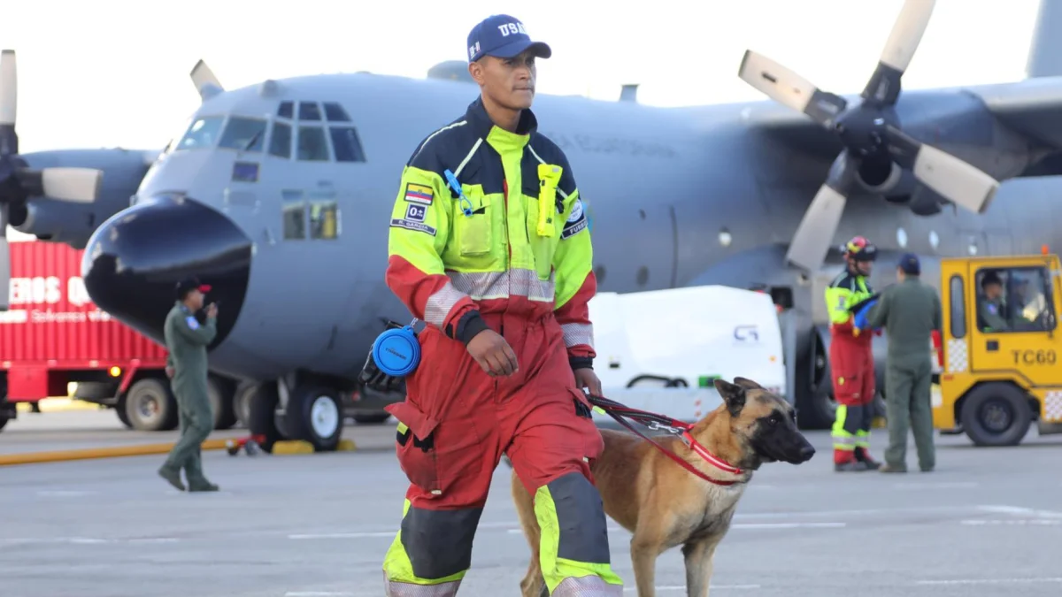 Aquí tienes un pie de foto breve, objetivo y neutral que complementa el contexto:

Un bombero camina con un perro de rescate en la pista de Latacunga antes de viajar a Venezuela este jueves.