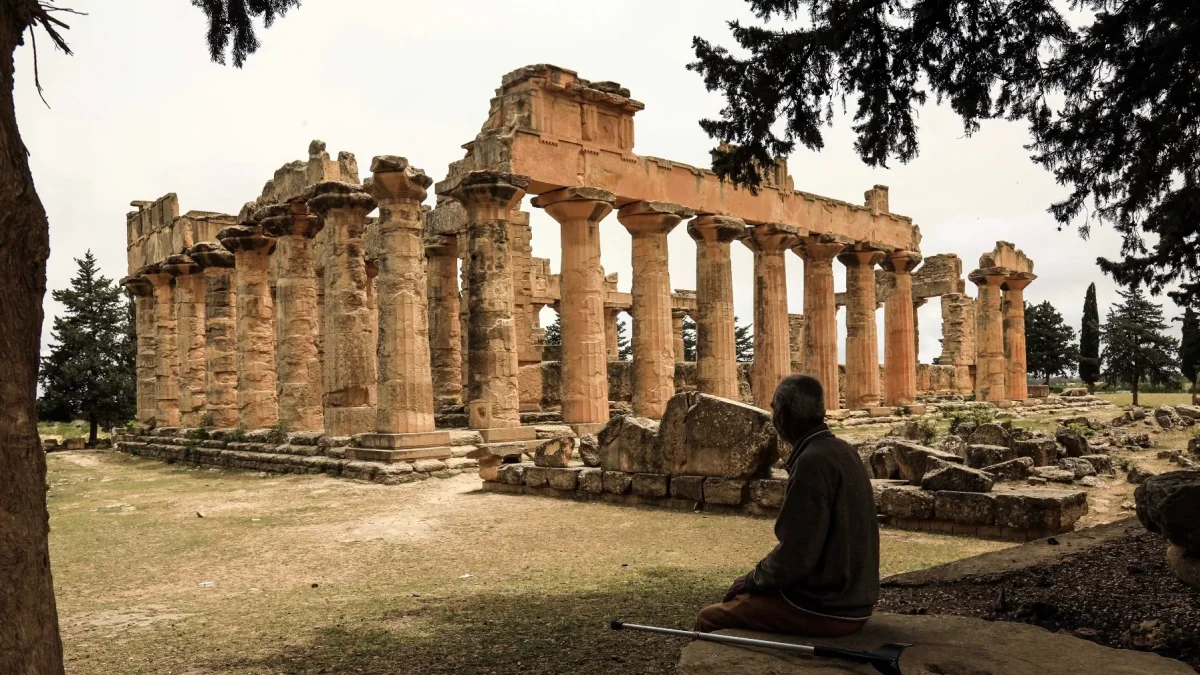 Un hombre se sienta a la sombra frente al Templo de Zeus en el sitio arqueológico de Cirene,en la costa mediterránea nororiental de Libia, el 18 de mayo de 2026.