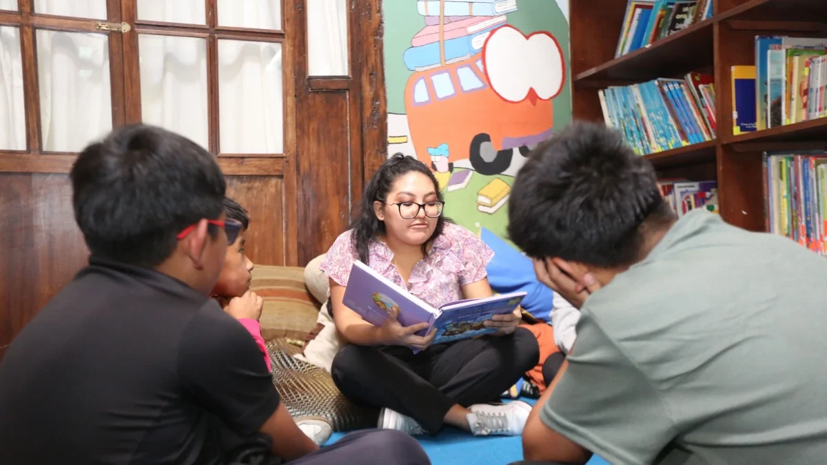 Erika Guaña, coordinadora de Casa Victoria, acompaña a niños en actividades de lectura en la biblioteca de San Roque, Quito.