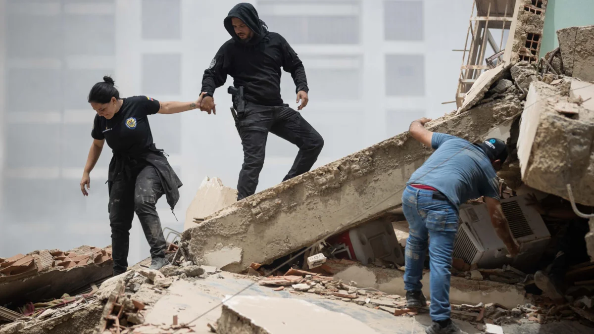 Personas caminan entre los escombros de edificios derrumbados en La Guaira tras los terremotos en Venezuela.