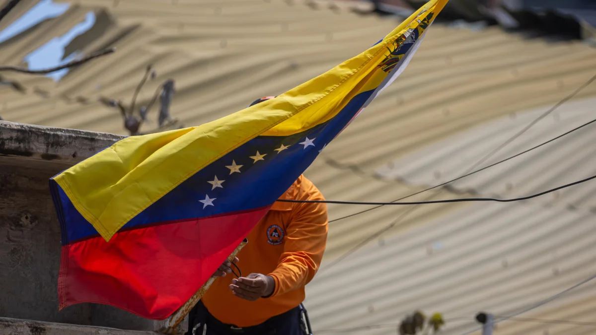 Un integrante de Protección Civil coloca la bandera de Venezuela en La Guaira tras los terremotos