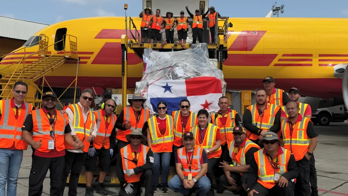 Personal de carga junto a un envío con la bandera de Panamá en un avión de DHL