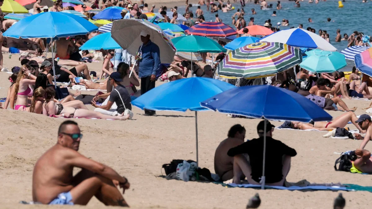 Turistas buscan sombra bajo sombrillas en playas europeas durante la ola de calor.